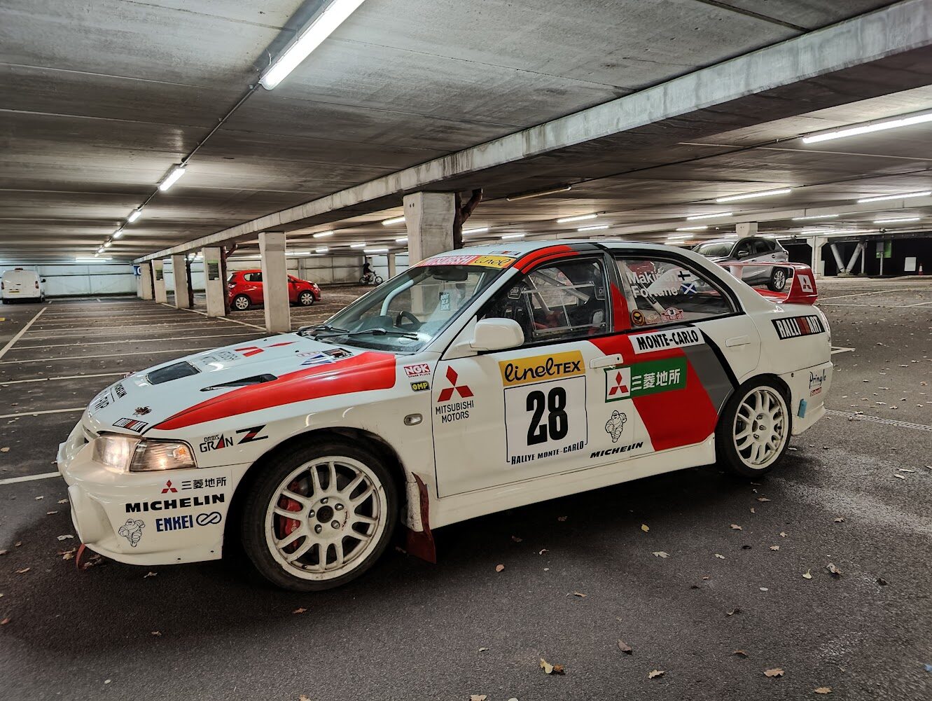 Mitsubishi Evo IV rally car side profile in Monte Carlo livery under car park lighting